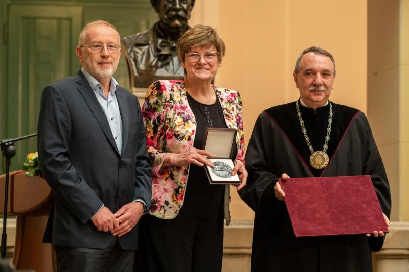 Karikó Katalin biokémikus, kutatóbiológus, a koronavírus elleni mRNS-alapú oltóanyag egyik fejlesztője látható, miután átvette a Neumann János professzori címet Czigány Tibor rektortól (jobbra) és Beck Györgytől, a Neumann János Számítógép-tudományi Társaság elnökétől (balra) a Budapesti Műszaki és Gazdaságtudományi Egyetem ünnepi szenátusi ülésén az egyetem aulájában 2023. június 3-án. A kép forrása: Fotó: BME – Geberle Berci
